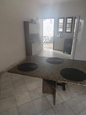 Cocina con encimera de granito, tres hornillas y un refrigerador.