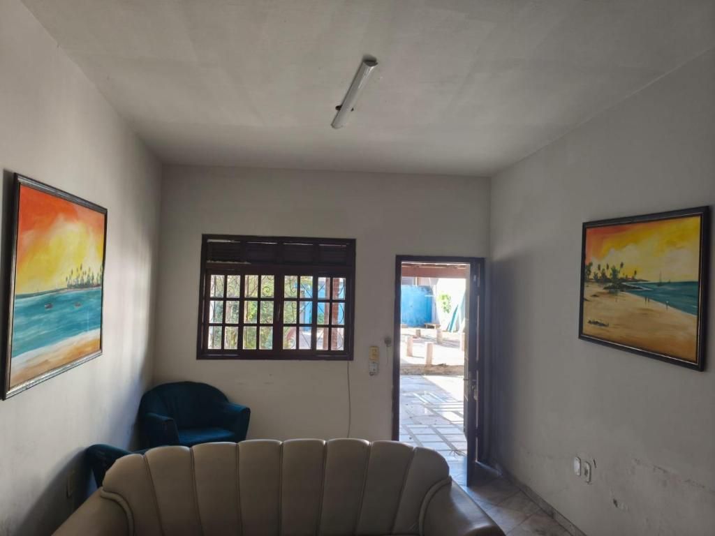 Quarto com sofá, uma cadeira e duas janelas com persianas.