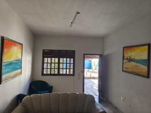 A room with a sofa, a chair, and two windows with blinds.