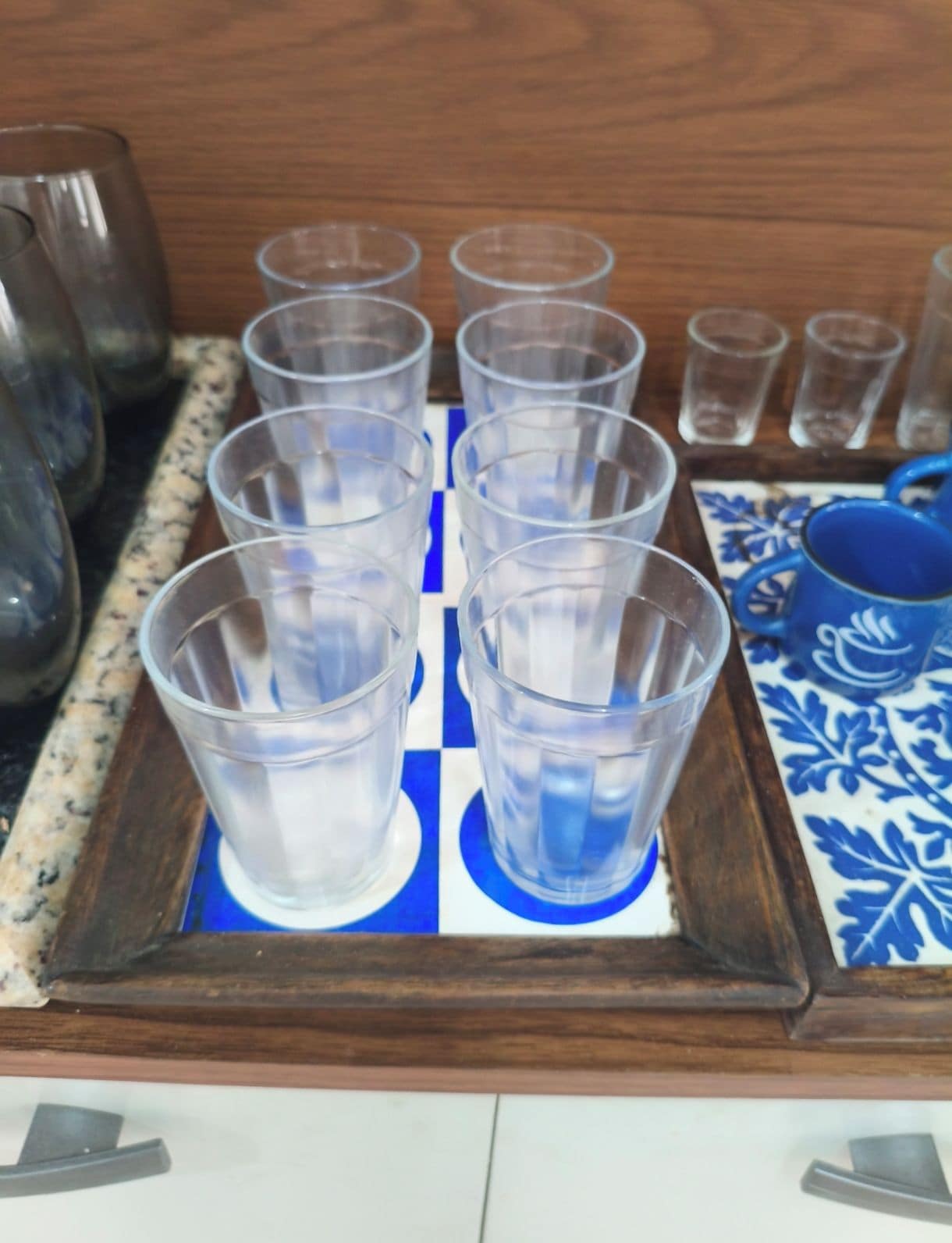 A tray with multiple clear plastic cups arranged on a blue and white patterned surface.