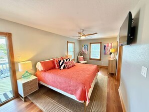 A bedroom with a bed, nightstands, a ceiling fan, a TV, and artwork on the walls. - 8BR Ocean Views | Private Pool | Hot Tub | Beach (Nags Head)
