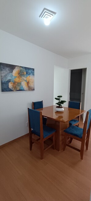 Un coin repas avec une table ronde, quatre chaises, une plante en pot et un tableau accroché au mur.