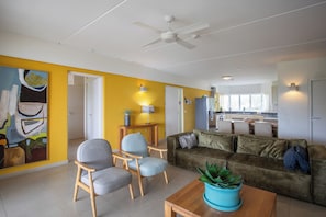 A modern living room with a sofa, chairs, a coffee table, and a ceiling fan. - Blue Bay Beachfront Apartment (Willemstad)