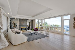 Un salon spacieux doté d’une cheminée, de grandes fenêtres et offrant une vue sur l’extérieur.