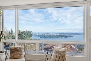 A room with a large window overlooking a cityscape and water. - Luxury 6BR West Van Villa and Sky-High Ocean Views (West Vancouver)