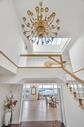 Un intérieur spacieux agrémenté d’un magnifique lustre, d’un escalier et offrant une vue sur la ville grâce à de grandes fenêtres.