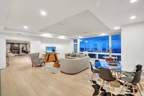 Ein modernes Wohnzimmer mit Essbereich, großen Fenstern und Blick auf die Stadt.