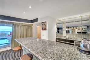 Une cuisine moderne dotée de plans de travail en granit, d’une cuisinière en acier inoxydable et d’un grand îlot central avec des tabourets.