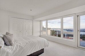 Une chambre avec une grande fenêtre, un lit et une porte.