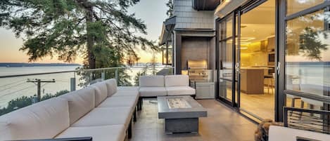 Une terrasse extérieure moderne, dotée d’un canapé, d’un foyer et offrant une vue sur l’océan.