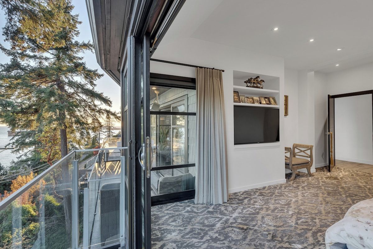 Una habitación con un ventanal, una silla y una cama.