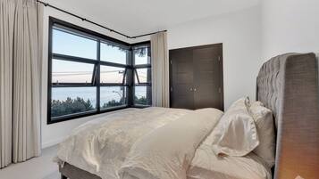 Un dormitorio con un ventanal grande, una cama con cabecero y un armario.