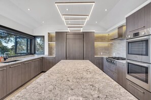 Una cocina moderna con una isla grande, electrodomésticos integrados y vistas al exterior.