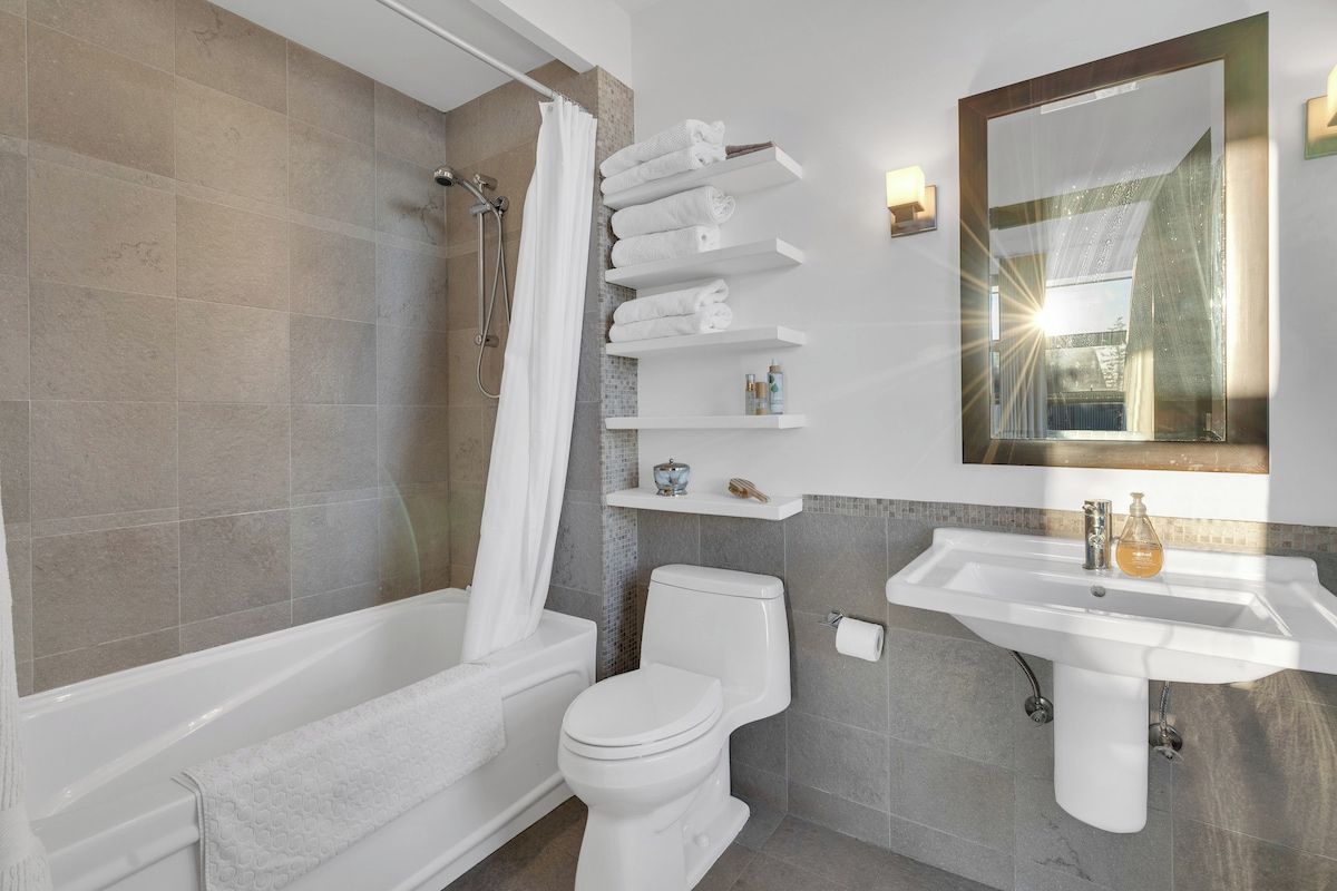 Une salle de bain moderne avec une baignoire, des toilettes et un lavabo. On y trouve également des porte-serviettes et un miroir au mur.