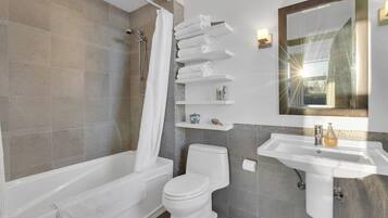 Une salle de bain moderne avec une baignoire, des toilettes et un lavabo. On y trouve également des porte-serviettes et un miroir au mur.