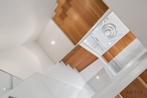 A modern interior with a central spiral staircase, wooden paneling, and a glass ceiling. - Luxury 5BR Mansion | Pool, Sauna & Scenic Views (West Vancouver)