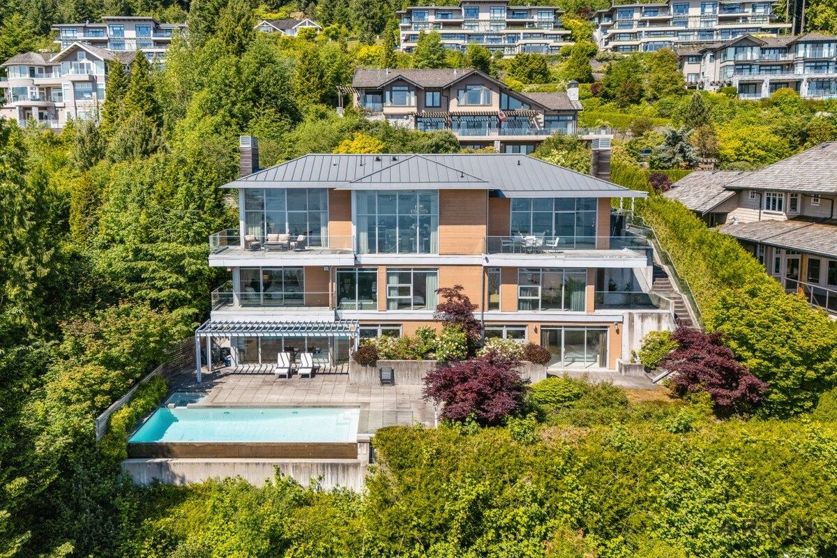 Ein modernes, zweistöckiges Haus mit großer Glasfassade, Schwimmbad und üppigem Garten.