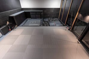 Ein modernes Interieur mit einem großzügigen, offenen Raum, einer Sitzecke mit Kissen und einem kleinen Trainingsbereich mit Matten.