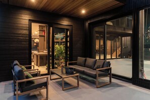 A modern interior with a sofa, chairs, and a coffee table. There is a glass door leading to a kitchen area with a dining table and chairs. - 3BR Sea-to-Sky Retreat with Rec Room, Near Creek (Britannia Beach)