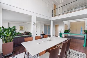 Ein geräumiger Essbereich mit hoher Decke, einem Balkon und Blick ins Innere.