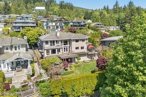 A residential area with multiple houses, a well-maintained lawn, and a variety of trees. - Luxe West Van Estate | Theater, Garden & Terraces (West Vancouver)