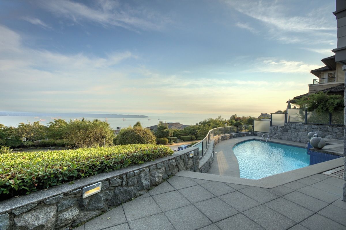 A swimming pool with a stone wall and a view of the sea.