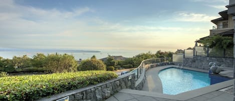 A swimming pool with a stone wall and a view of the sea.