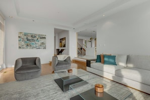 Ein modernes Wohnzimmer mit einem grauen Sofa, einem grauen Sessel und einem Glastisch.