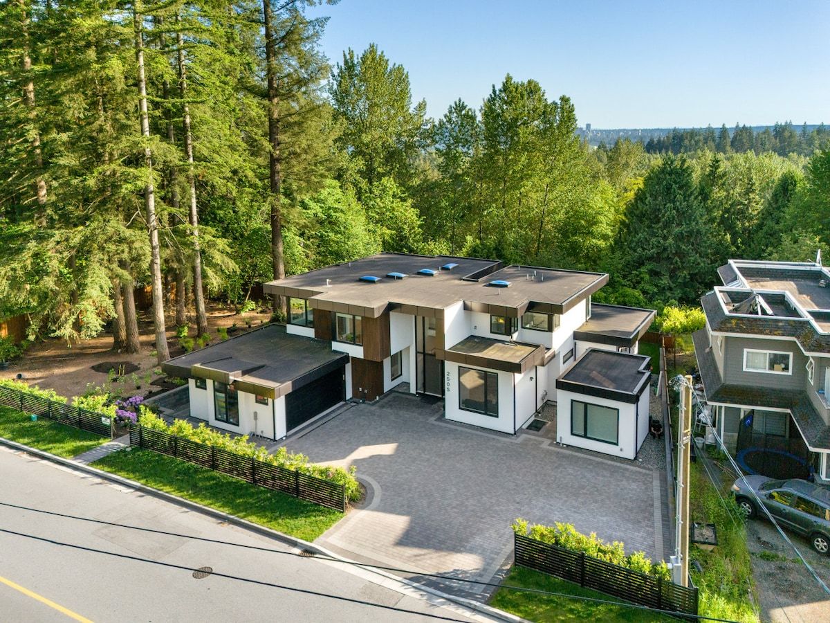 Un ensemble résidentiel moderne comprenant plusieurs maisons, une allée et une forêt environnante.