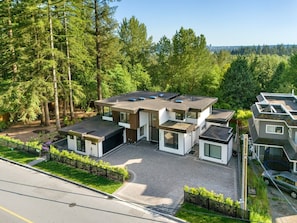 A modern residential complex with multiple houses, a driveway, and a surrounding forest. - Edgemont 5BR Designer Getaway with Home Theater (North Vancouver)