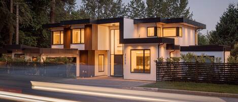 Une maison moderne à deux étages, dotée d’un toit plat, de grandes fenêtres et d’une allée.