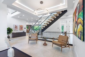 Een ruime lobby met een trap, zithoek en kunstwerken aan de muur.