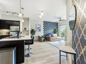 A modern kitchen with a central island, bar stools, and a dining area with a sofa and coffee table. - Cozy 1-bedroom apartment in the historic Bishop Arts area. (Dallas)