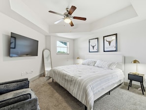 A bedroom with a bed, a ceiling fan, a TV, a window, and framed artwork on the wall. - Cozy 1-bedroom apartment in the historic Bishop Arts area. (Dallas)