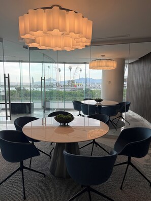 Une salle de conférence moderne avec un mur en verre, une table ronde et des chaises noires.