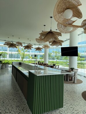 A modern interior with a central island, hanging rattan lamps, and a large window offering a view of greenery. - Amazing beachfront luxury apartment, brand new, amenities, gym, restaurant. (Nuevo Nayarit)