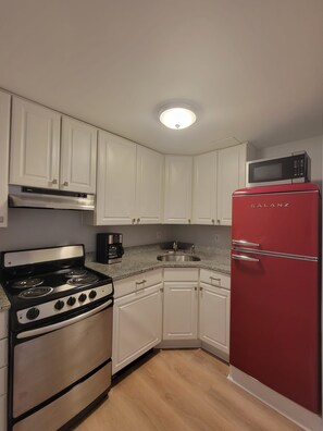 A kitchen with white cabinets, a red refrigerator, a stove, and a microwave. - Adorable 1-bedroom apartment in lovely Swampscott perfect for getaway (Swampscott)