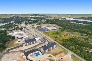 A large commercial building with multiple parking lots, a swimming pool, and a hilly landscape in the background. - Lakefront Retreat at Table Rock Lake (Kimberling City)