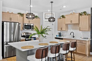 Une cuisine moderne dotée d’appareils électroménagers en acier inoxydable, d’un îlot central avec des tabourets de bar et de meubles de rangement en bois.