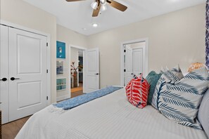 A bedroom with a bed, pillows, a ceiling fan, and a hallway leading to a bathroom. - Lakefront Retreat at Table Rock Lake (Kimberling City)