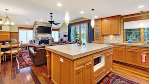 A spacious kitchen with wooden cabinets, a central island, and a dining area with a fireplace. - Three Kings Condo by Avantstay Walk To Slopes Shared Pool + Spa Near Main St (Park City)