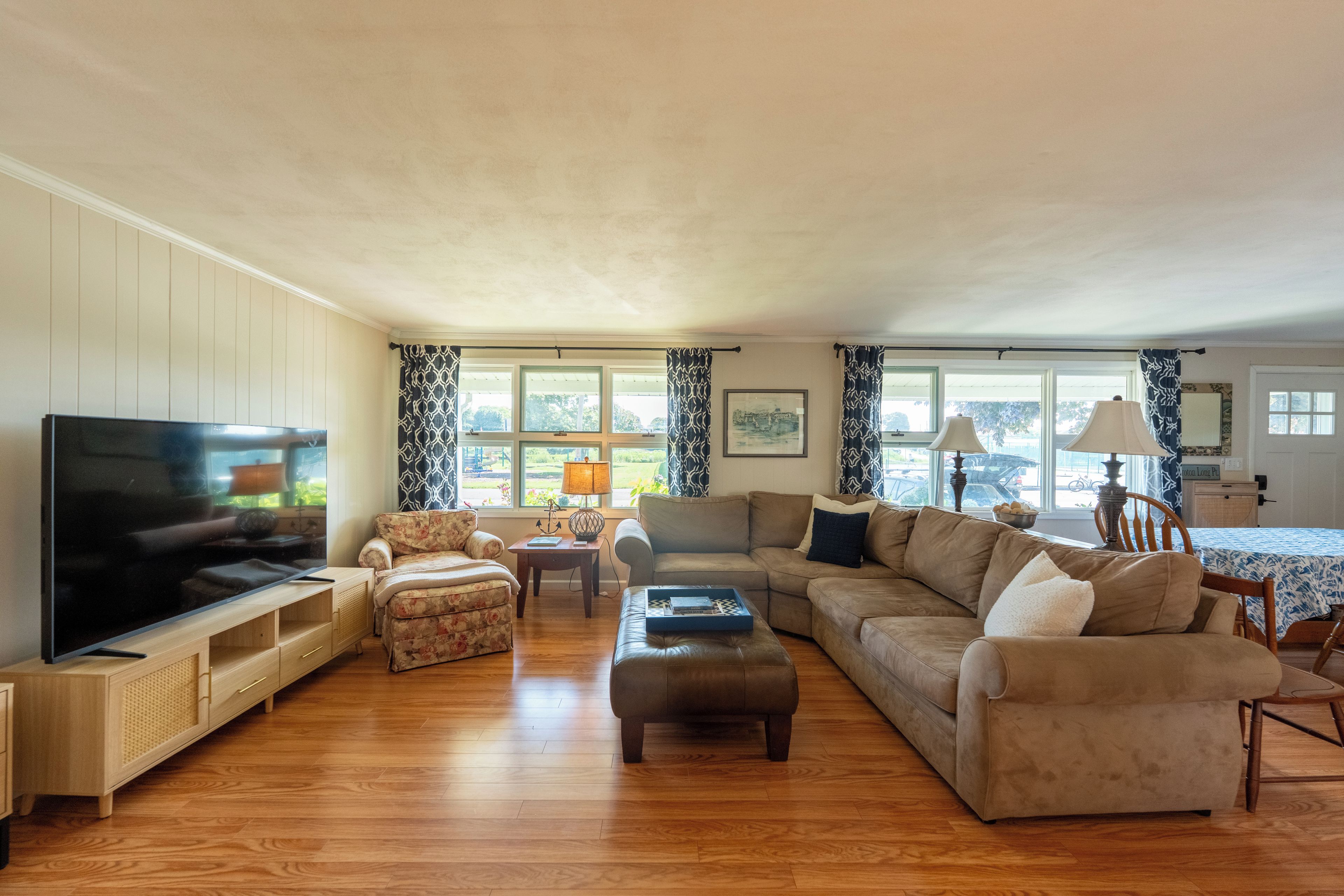 A living room with a flat-screen TV, a sofa, a coffee table, and a dining area with a table and chairs.