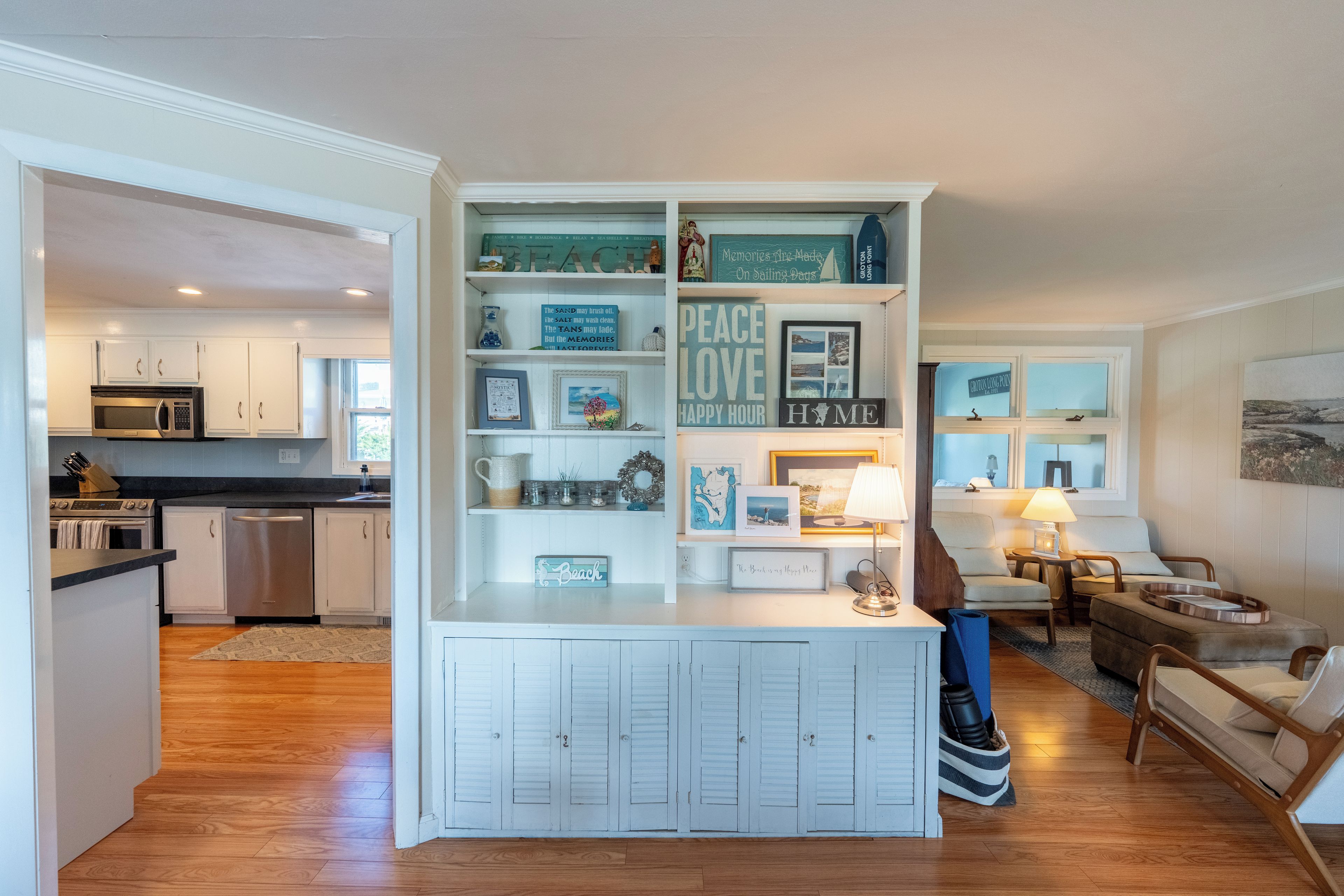 A modern kitchen with white cabinetry, a built-in microwave, and a dining area with a wooden table and chairs.