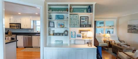 A modern kitchen with white cabinetry, a built-in microwave, and a dining area with a wooden table and chairs.