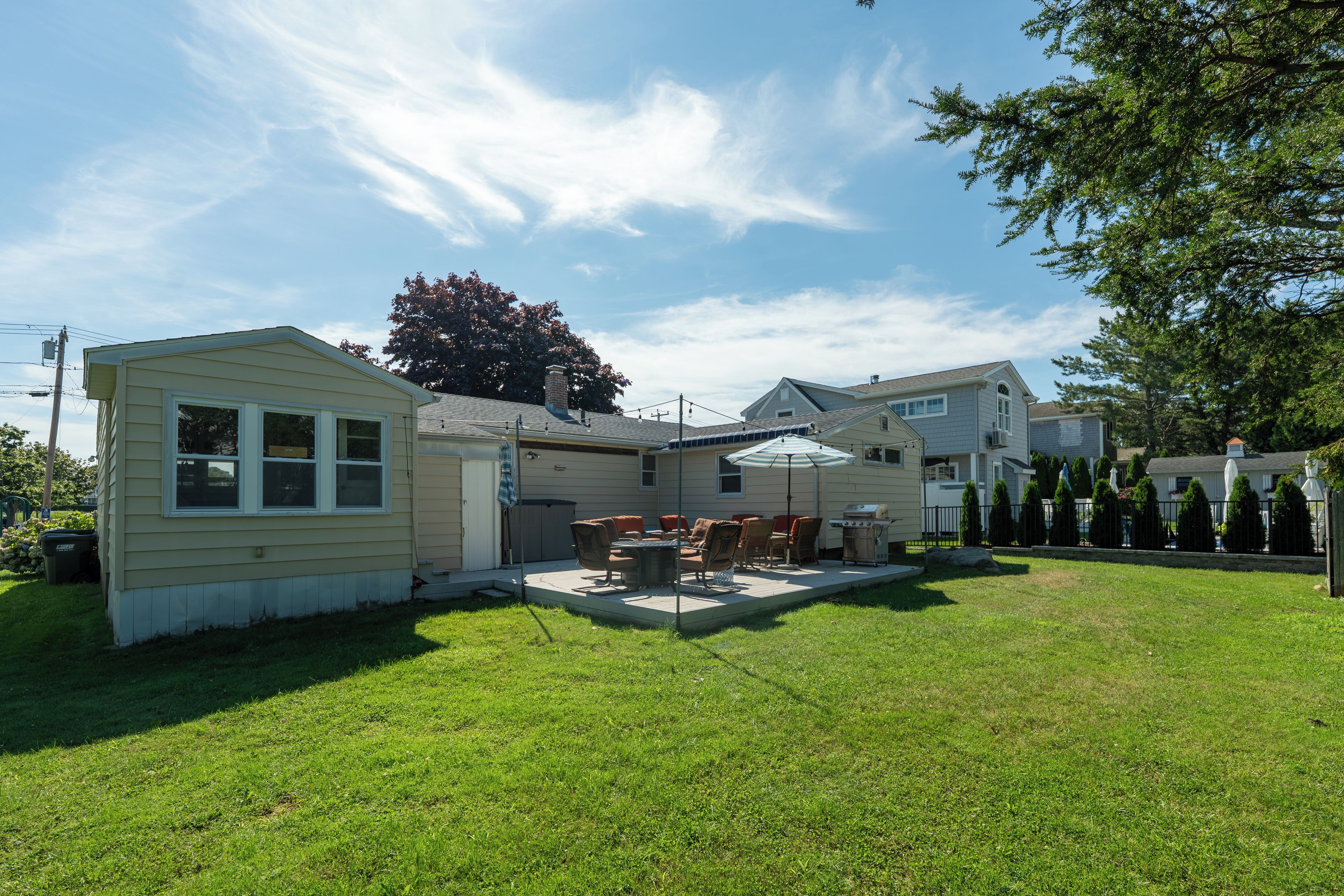 A residential backyard with a patio, outdoor furniture, and a grill.