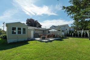 A residential backyard with a patio, outdoor furniture, and a grill.