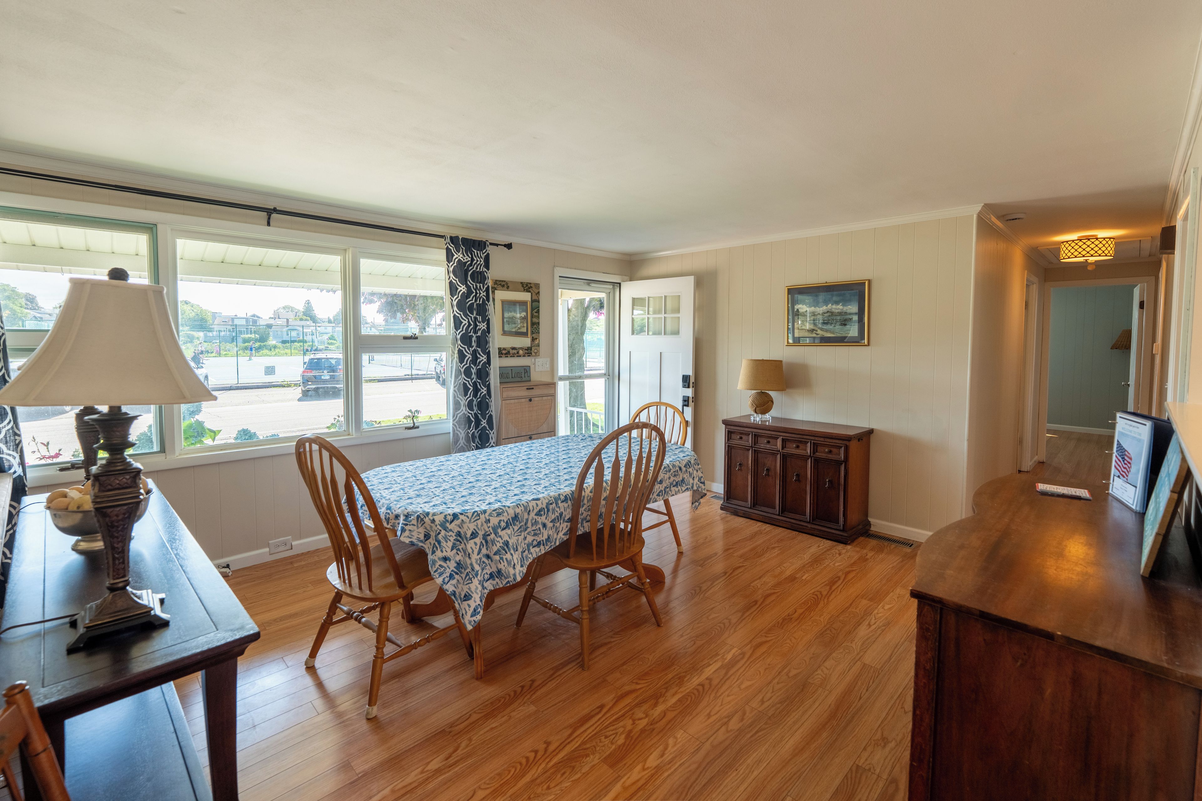 Un comedor con una mesa dispuesta para cuatro, sillas de madera, una lámpara y vistas al exterior.