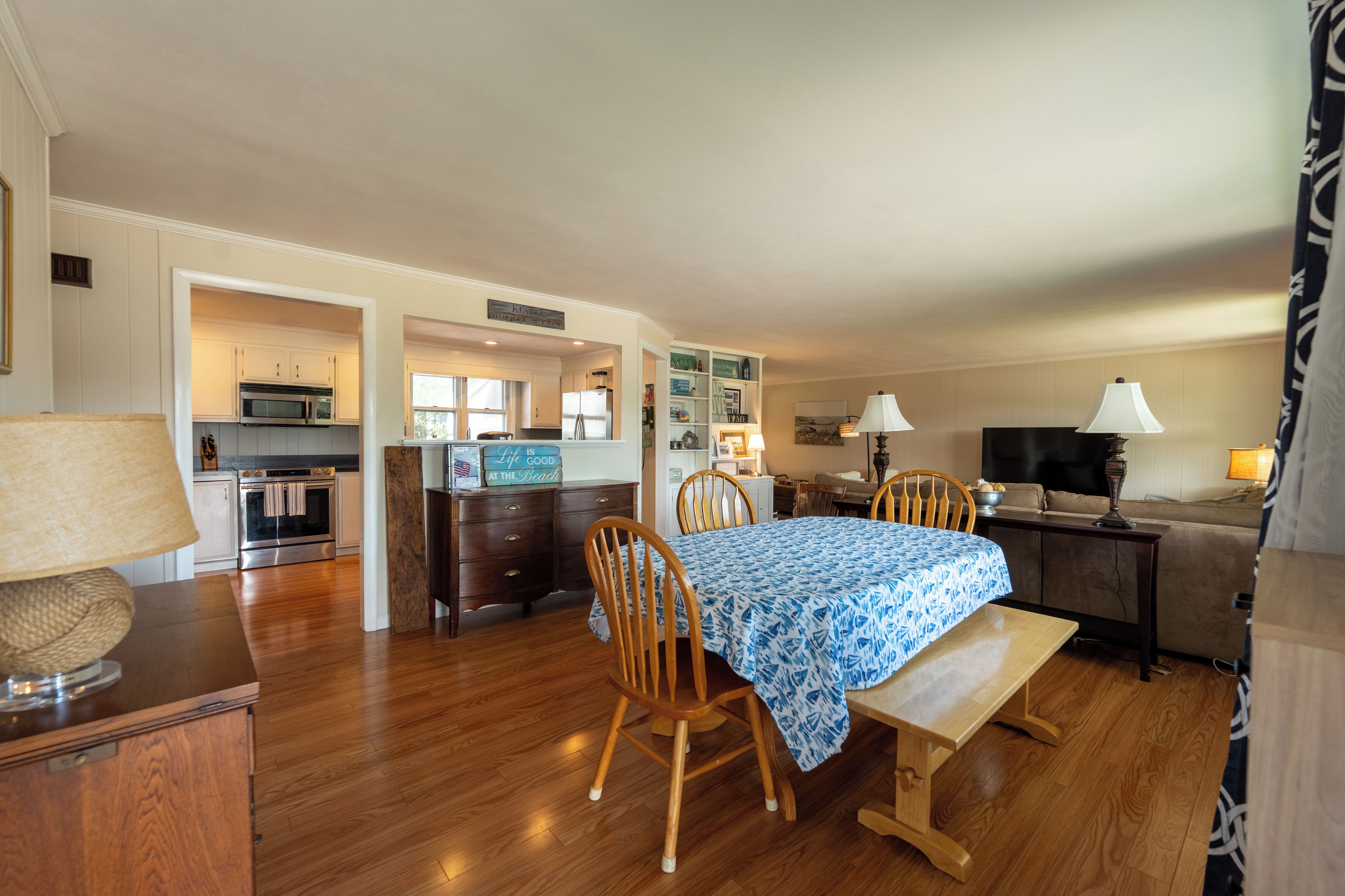 A spacious living area with a dining table, wooden chairs, a sofa, and a television.