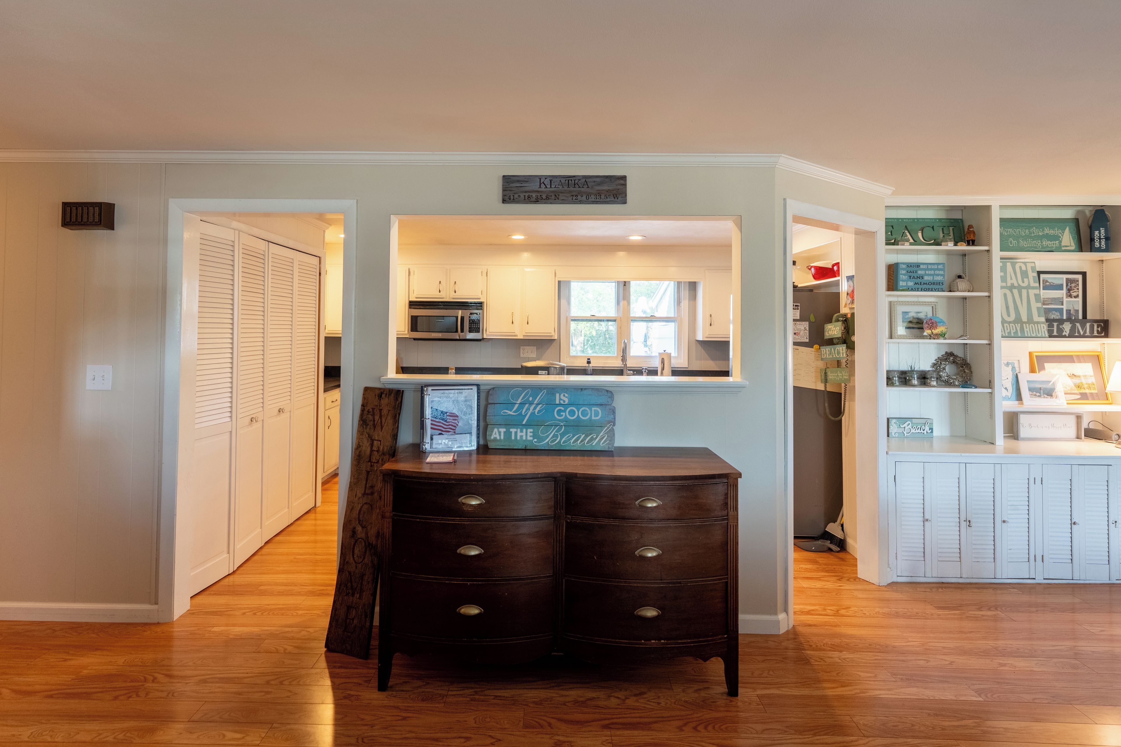 A kitchen with white cabinets, a microwave, and a chalkboard sign.