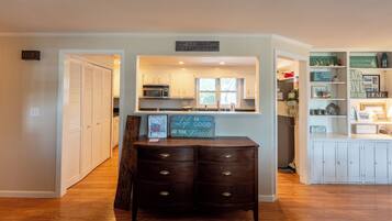 A kitchen with white cabinets, a microwave, and a chalkboard sign.